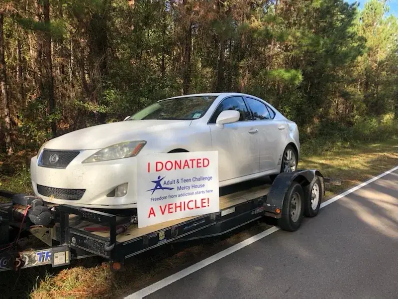 A donated sedan secured on a flatbed trailer for pickup